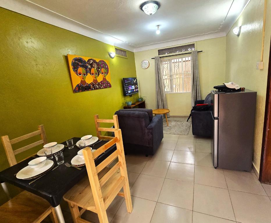 a kitchen and living room with a table and a refrigerator at MildVille Apartments in Hoima