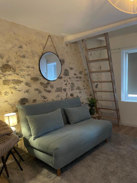 a living room with a couch and a mirror at Duplex de caractère in Coutances