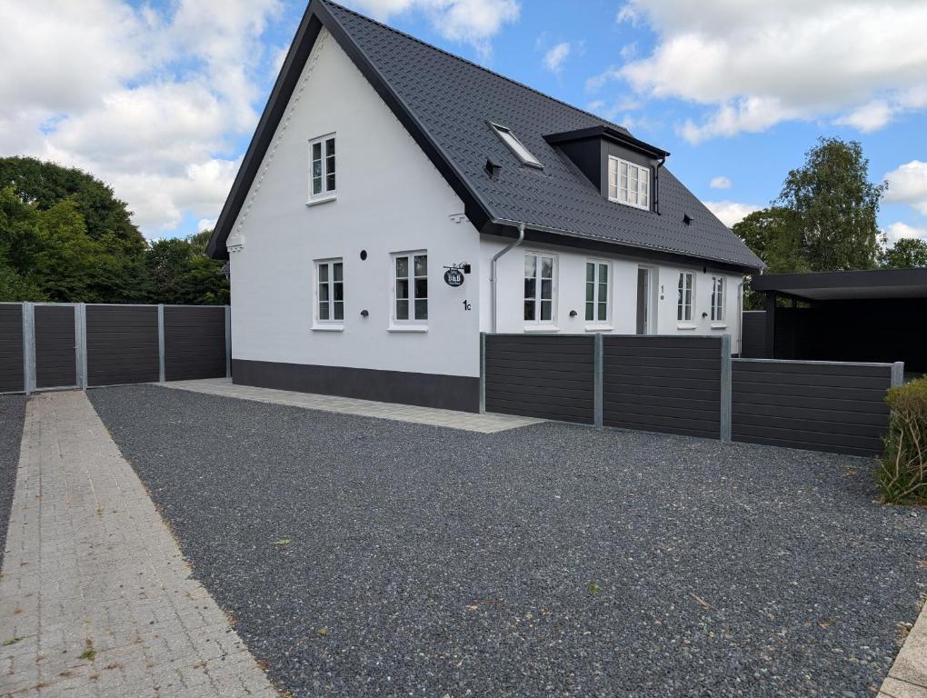 a white house with a black roof and a driveway at Kølkær B&B in Kølkær