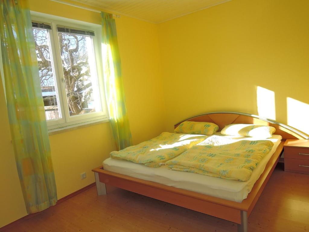 a bedroom with a bed with yellow walls and a window at Stadtnahe Landwohnung in Klagenfurt
