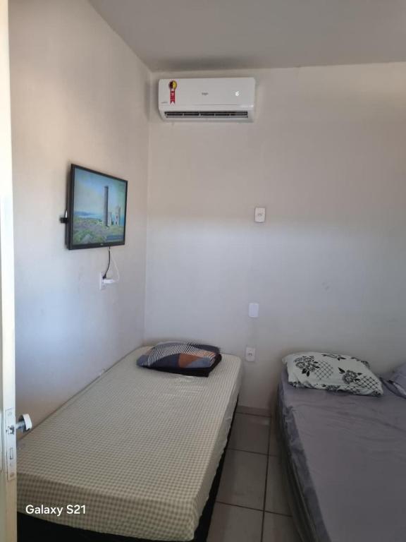 ein Schlafzimmer mit zwei Betten und einem Fernseher an der Wand in der Unterkunft Ney kitnet in Pirapora