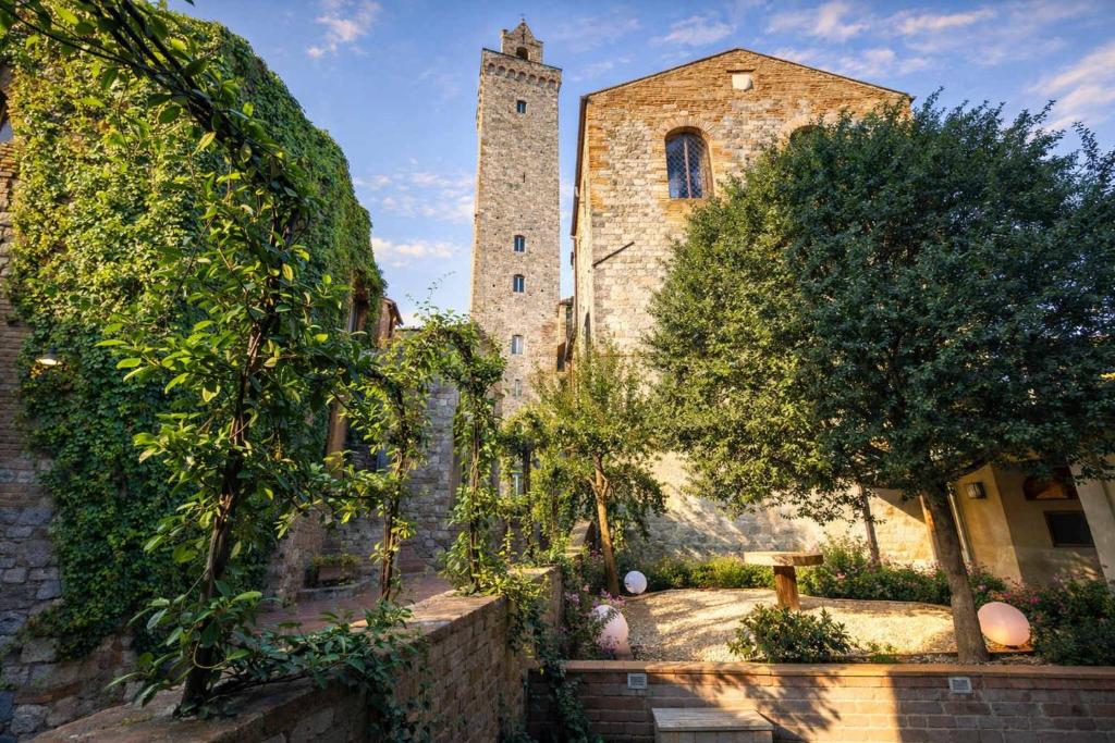 an old stone building with a tower and trees at Casa Costarella - San Gimignano in San Gimignano