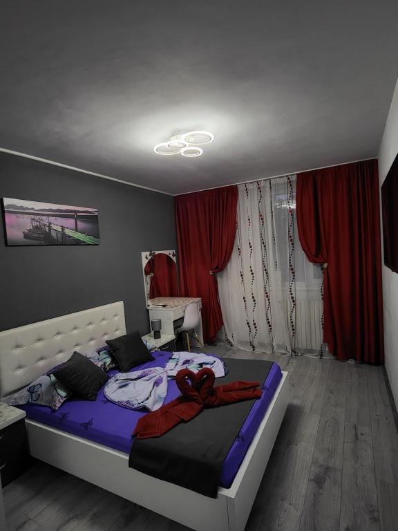 a bedroom with a large bed with red curtains at Apartament Cristian Relax in Olimp