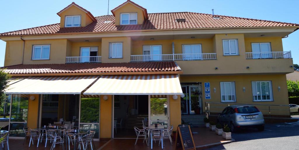 a building with tables and chairs in front of it at A Fontiña in Montalvo