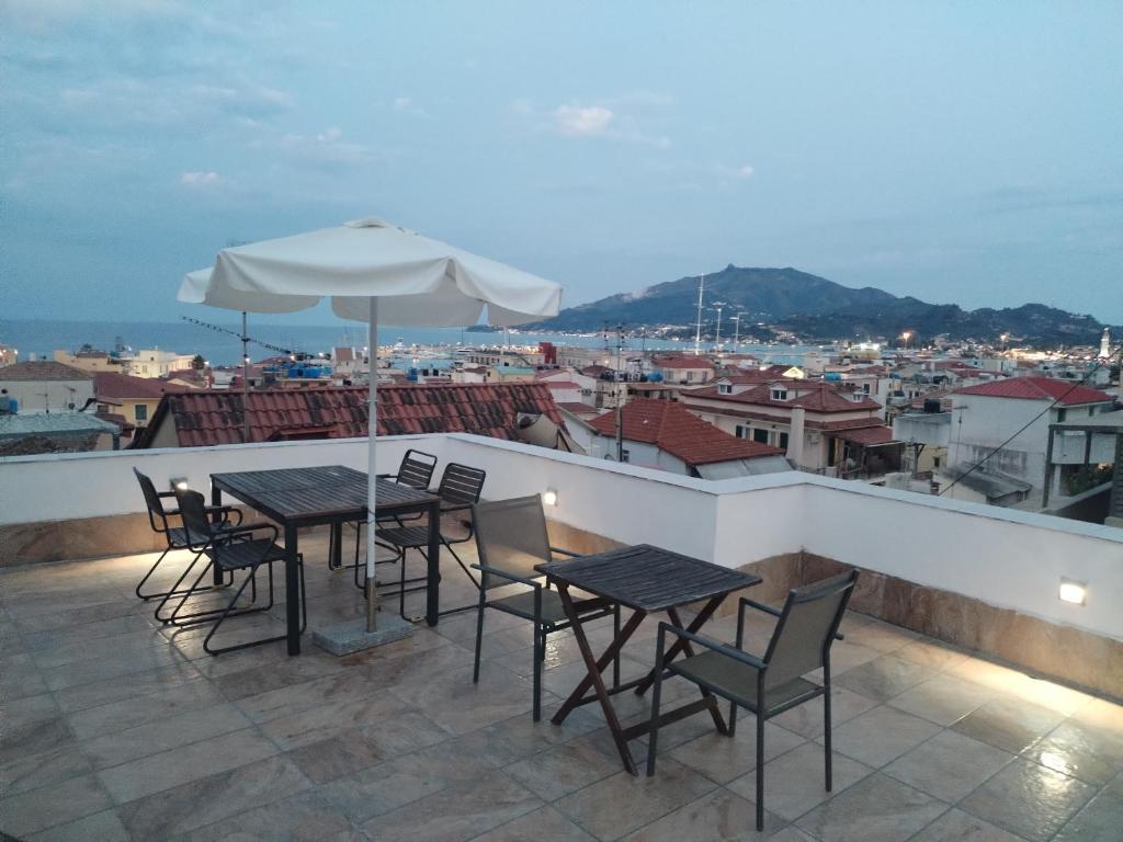 a patio with tables and chairs and an umbrella at Zante Art de l'eau in Zakynthos