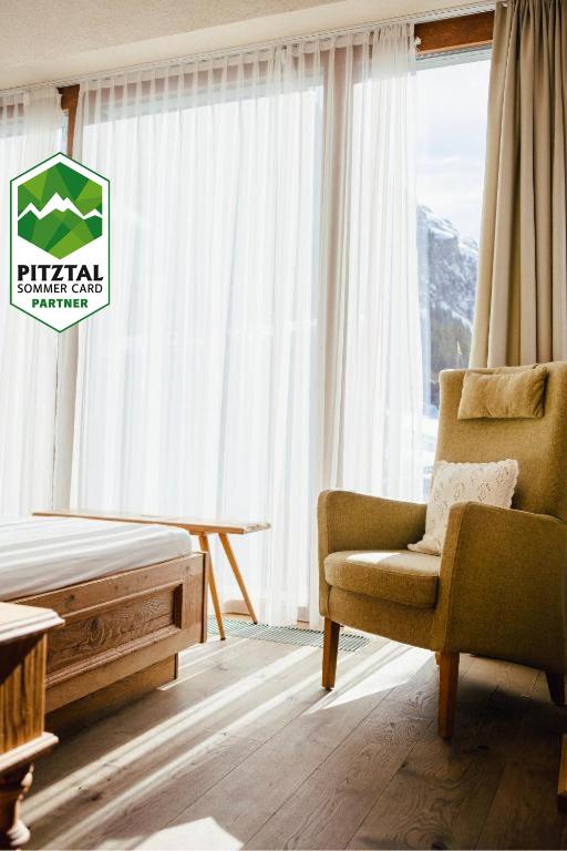 a living room with a chair and a window at bei Max - Hotel & Traditionshaus in Sankt Leonhard im Pitztal