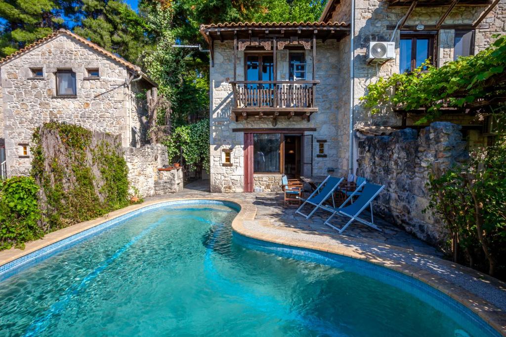 a house with a swimming pool in front of a house at Forest stone Villa with pool in Kriopigi