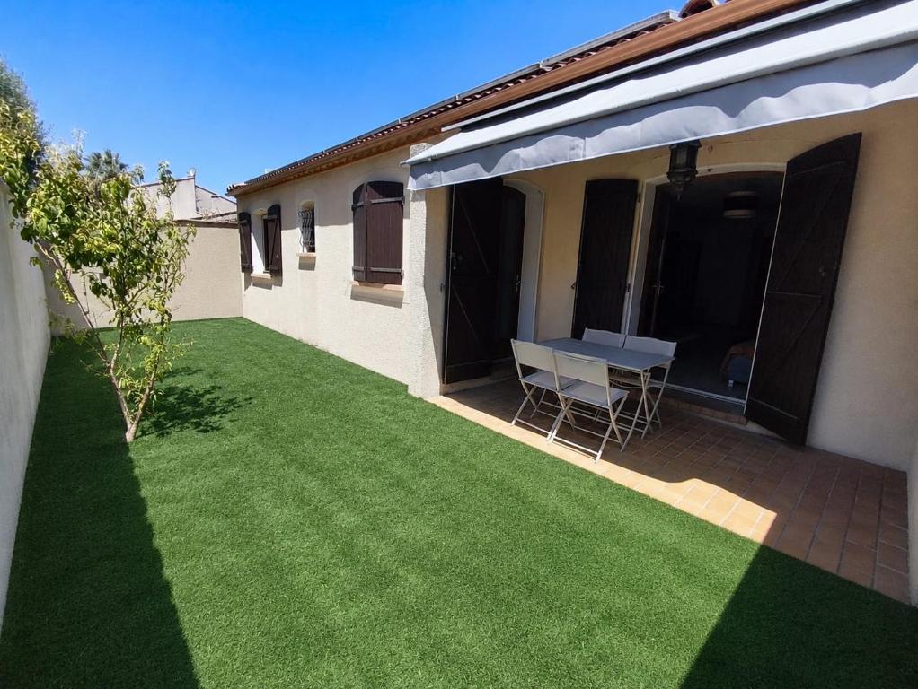 a backyard with a table and a lawn at Maison 80 m2 - proche des plages in Montpellier