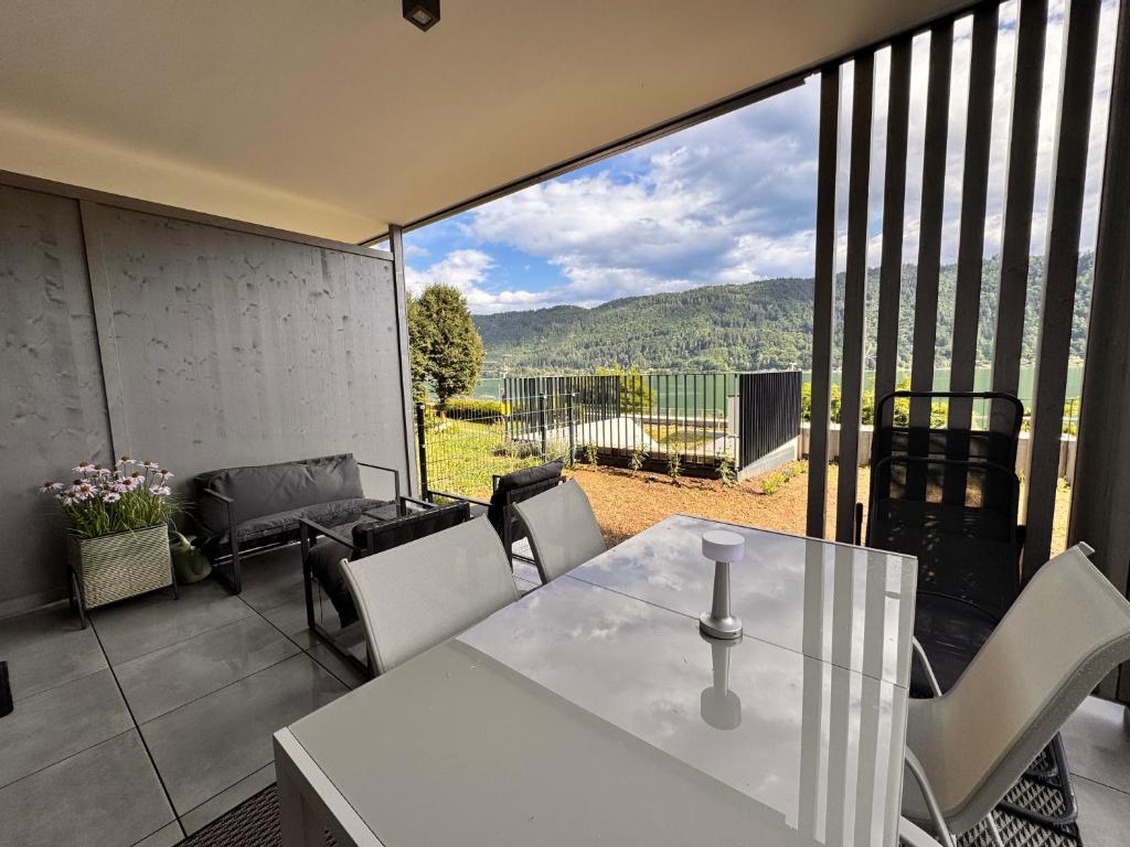 a glass table and chairs on a balcony with a view at Lakeside Garden Ossiacher See in Sattendorf