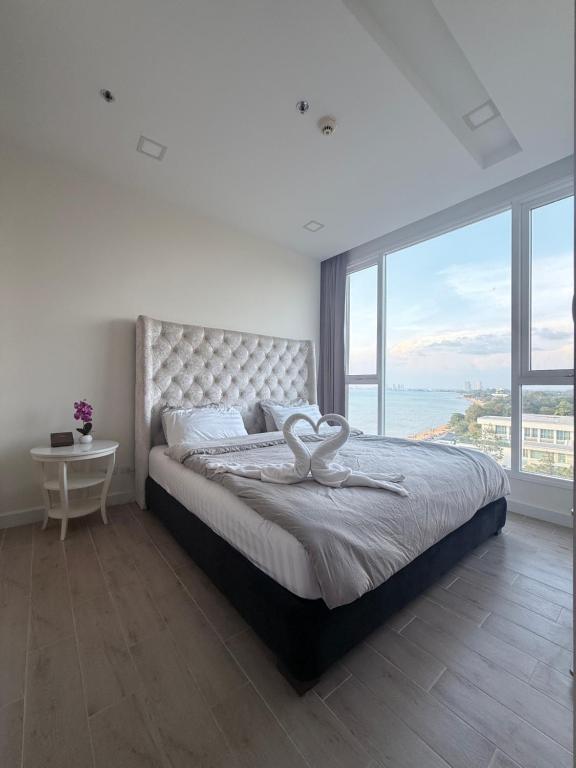 a bedroom with a large bed with a large window at Del Mare Bangsaley condo in Bang Sare