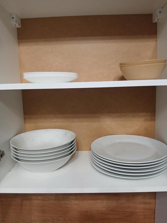 two plates and bowls are sitting on a shelf at Marshal Foch Apartment in Grudziądz