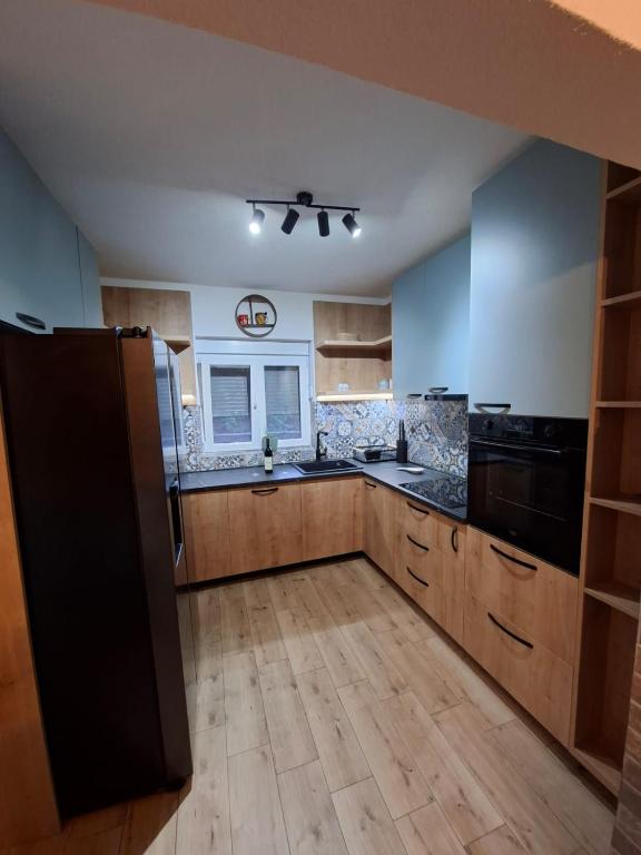 a large kitchen with wooden cabinets and black appliances at Apartman Jana in Žabljak