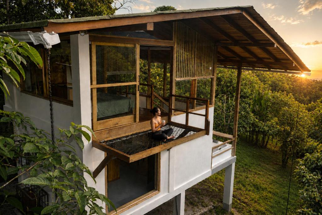 a woman sitting on the balcony of a tree house at MindoLoft Loft de lujo con servicio premium en Mindo in Mindo