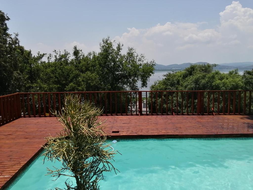 a swimming pool with a wooden deck next to at Mafofolozi Lodge in Hartbeespoort