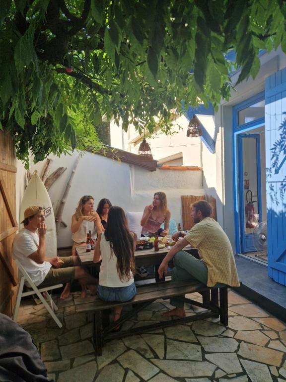 a group of people sitting around a picnic table at COTTAGE - Utopy Hostel in Capbreton