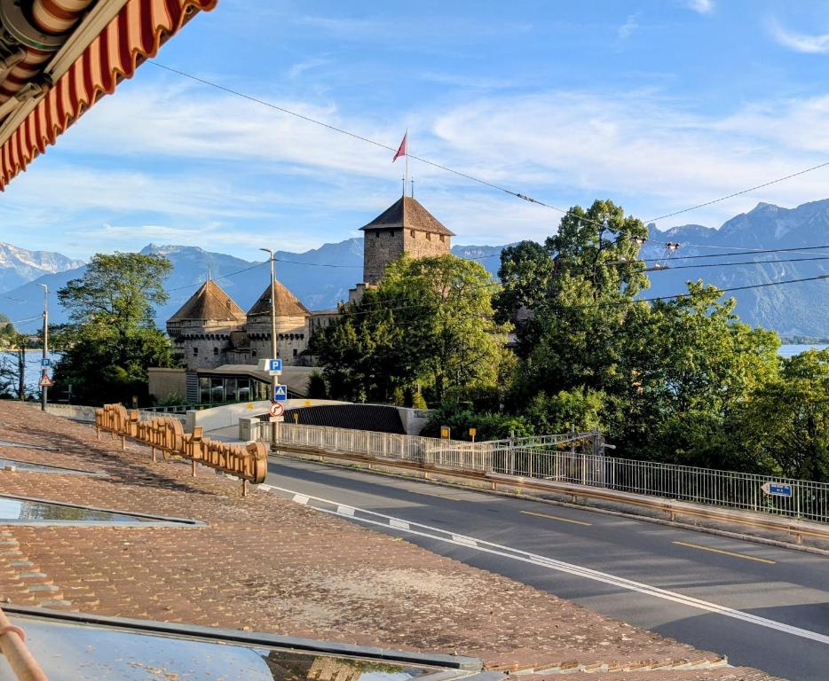 a road in front of a building with a castle at Chillon lake view by MK in Montreux