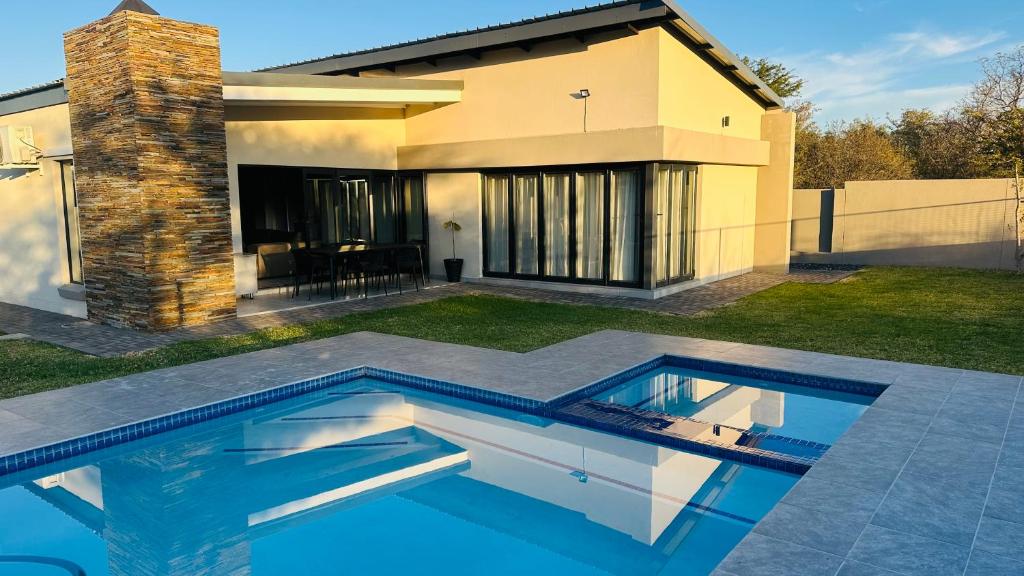 a swimming pool in front of a house at CELONIA VILLA - Euphoria Golf Estate in Naboomspruit