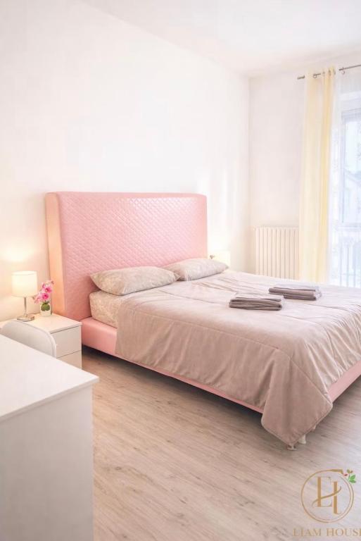 a bedroom with a large bed with a pink headboard at Liam House - Stanza 2 in Limbiate