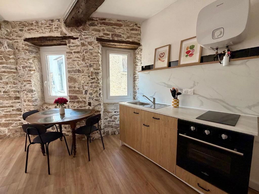 a kitchen with a table and a dining room at Le Cocon des pierres du Jaur in Saint-Pons-de-Thomières