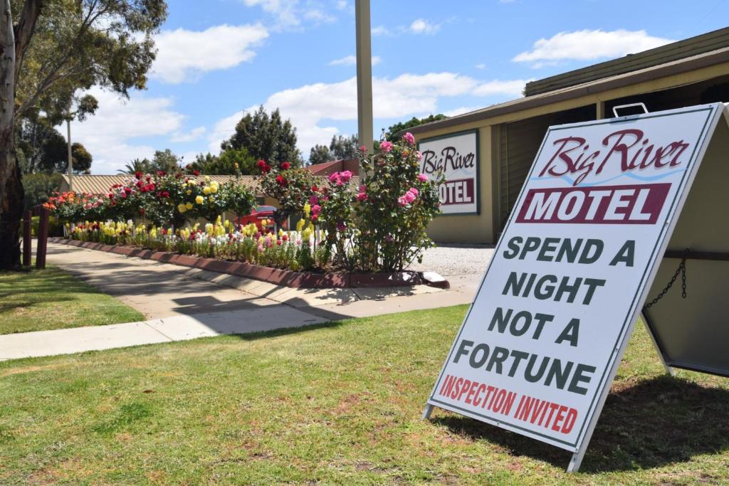 Una señal para un motel con flores en un patio en Big River Motel, en Echuca