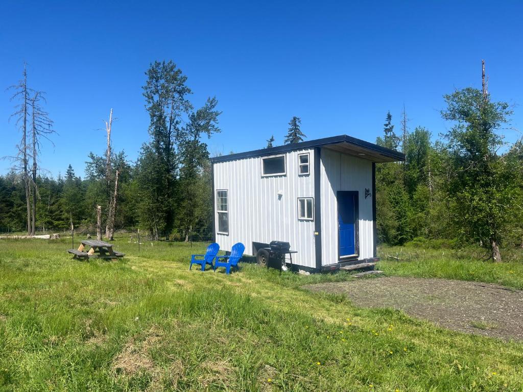 a tiny house in a field with two blue chairs at Tiny House Farm Stay Pets Welcome in Battle Ground