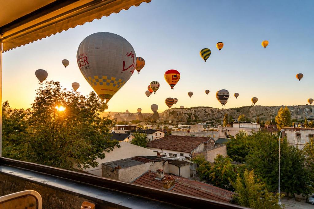 a group of hot air balloons flying over a city at Cappadocia Divin House in Göreme