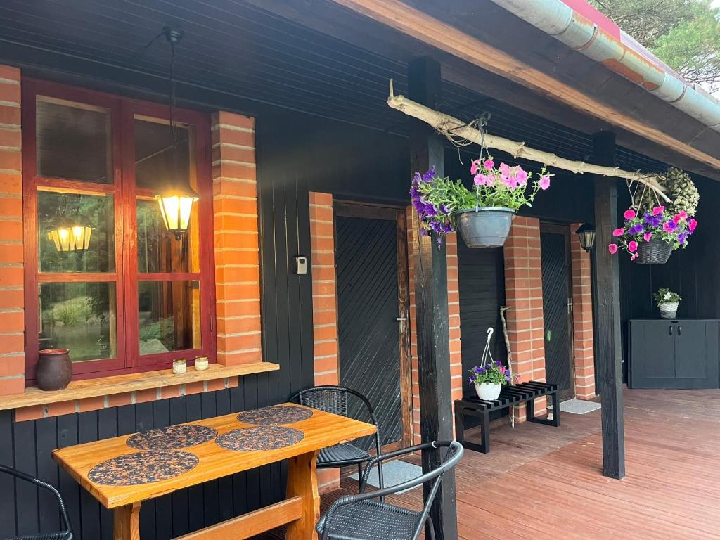 a patio with a wooden table and chairs and flowers at Ūbelītes in Pērkone