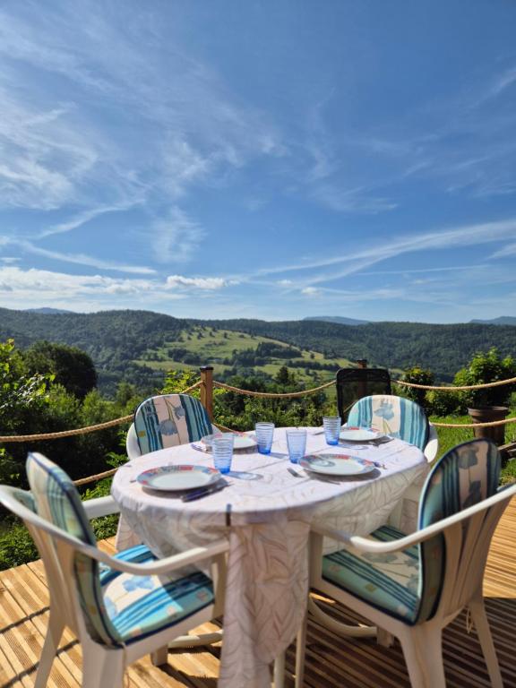 a white table with chairs on a deck with a view at Au Calme Des Vosges in Fresse-sur-Moselle