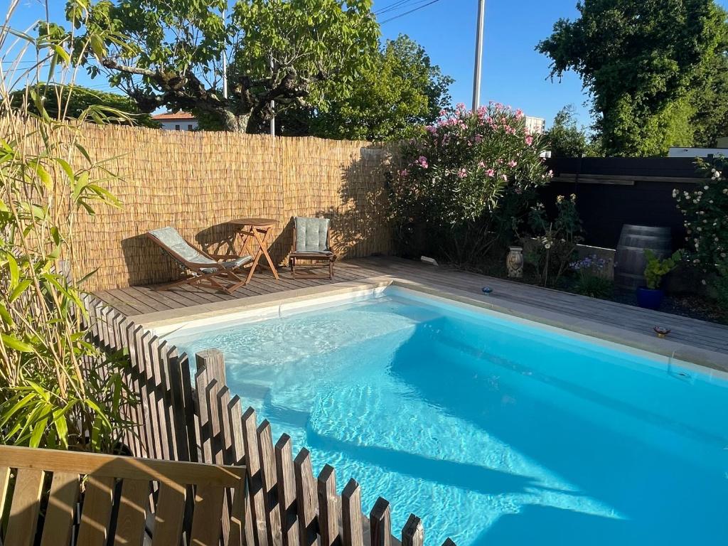 a swimming pool in a backyard with a table and chairs at Maison de vacances à Bordeaux in Le Haillan