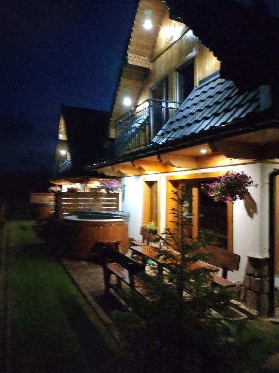 a house with a bench in front of it at night at Cicha Przystań Dzianisz z sauną i jakuzi na wyłączność in Dzianisz