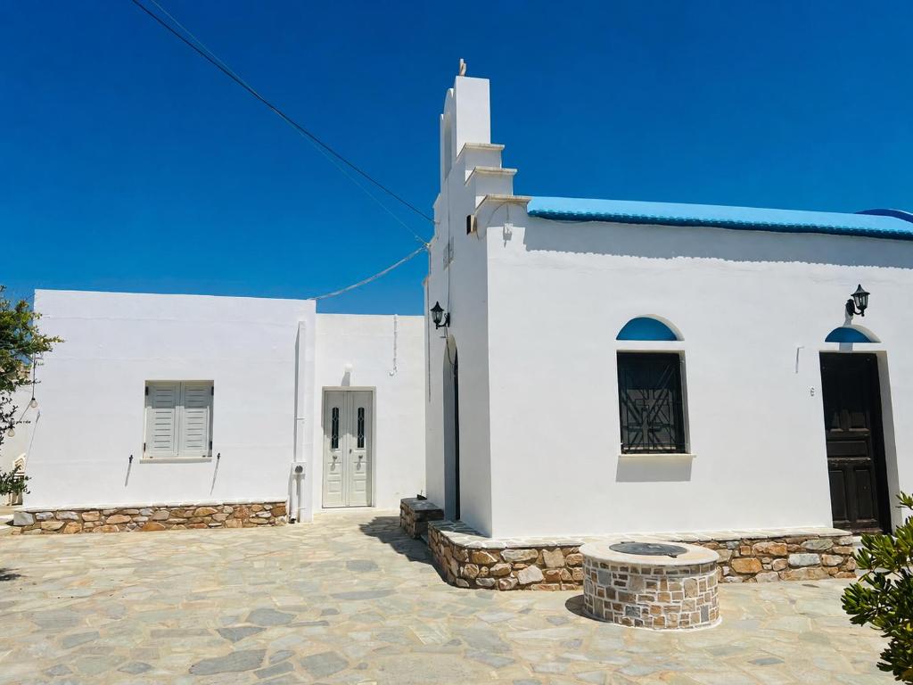 a white church with two doors and a stone courtyard at Divine Island Escape in Kini