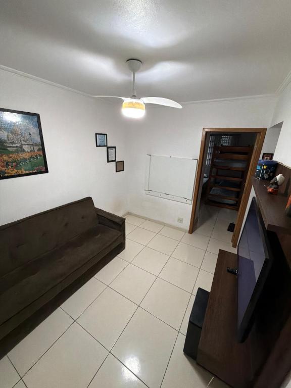 a living room with a couch and a tv at Lindo Apartamento na Guilhermina PG in Praia Grande