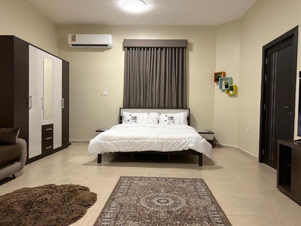 a bedroom with a bed with white sheets and pillows at Stylish 2BR Escape Near Muscat City Centre in Mawāliḩ
