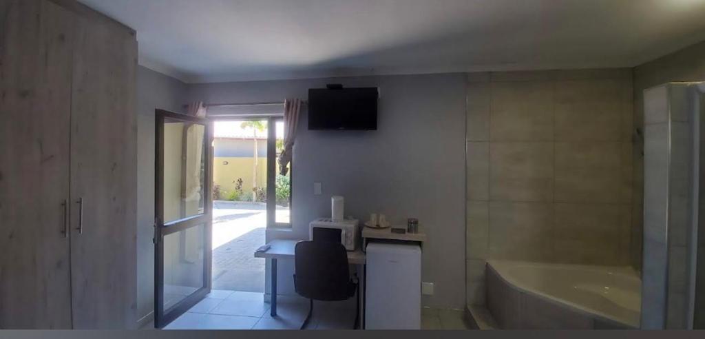 a bathroom with a tub and a table and a chair at Rundu Rainbow Guesthouse in Rundu