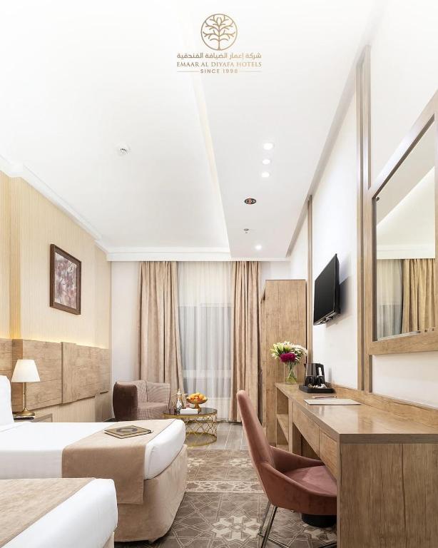 a hotel room with a bed and a desk at Vrtn home in Al Ghuşnah