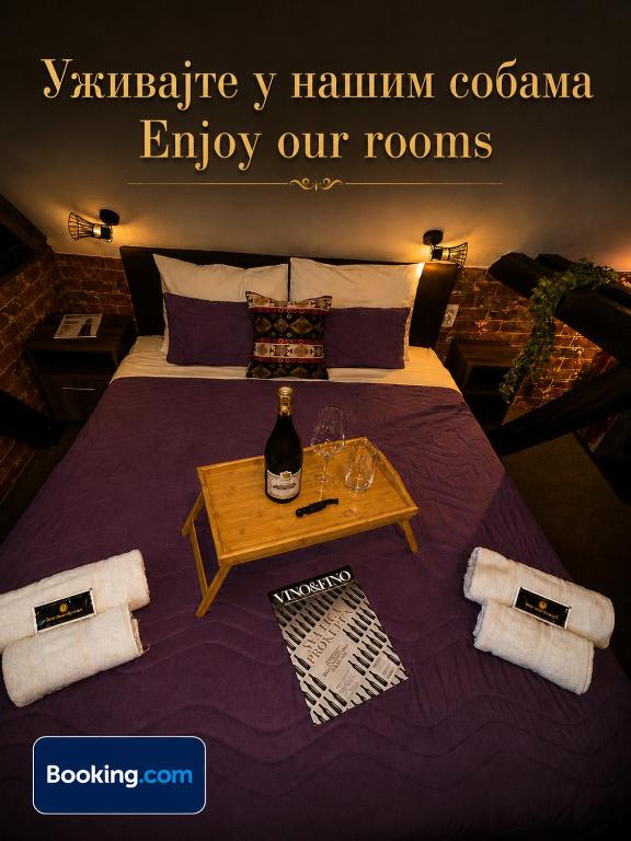 a bed with a table with a bottle and glasses on it at Rooms&Rest ПИРОЋЋ Heritage in Pirot