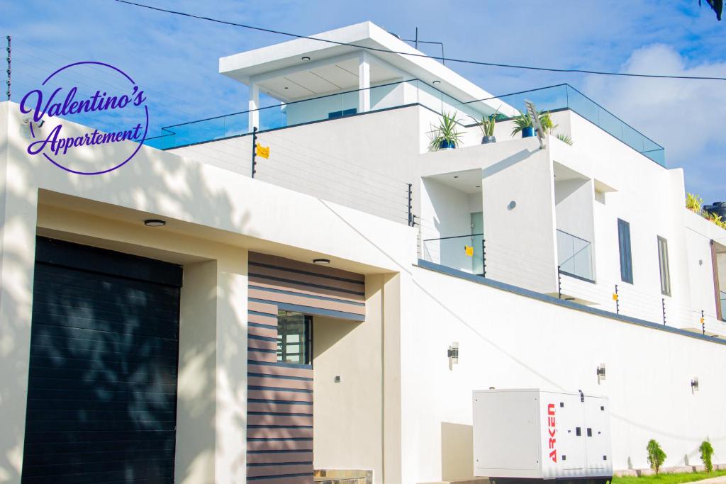 a white house with a garage at Valentinos Appartement Prestige in Agbodrafo