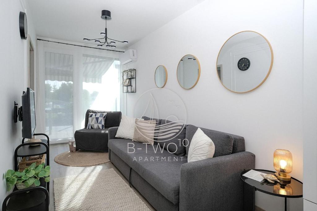 a living room with a couch and mirrors on the wall at B-Two10 in Balatonlelle