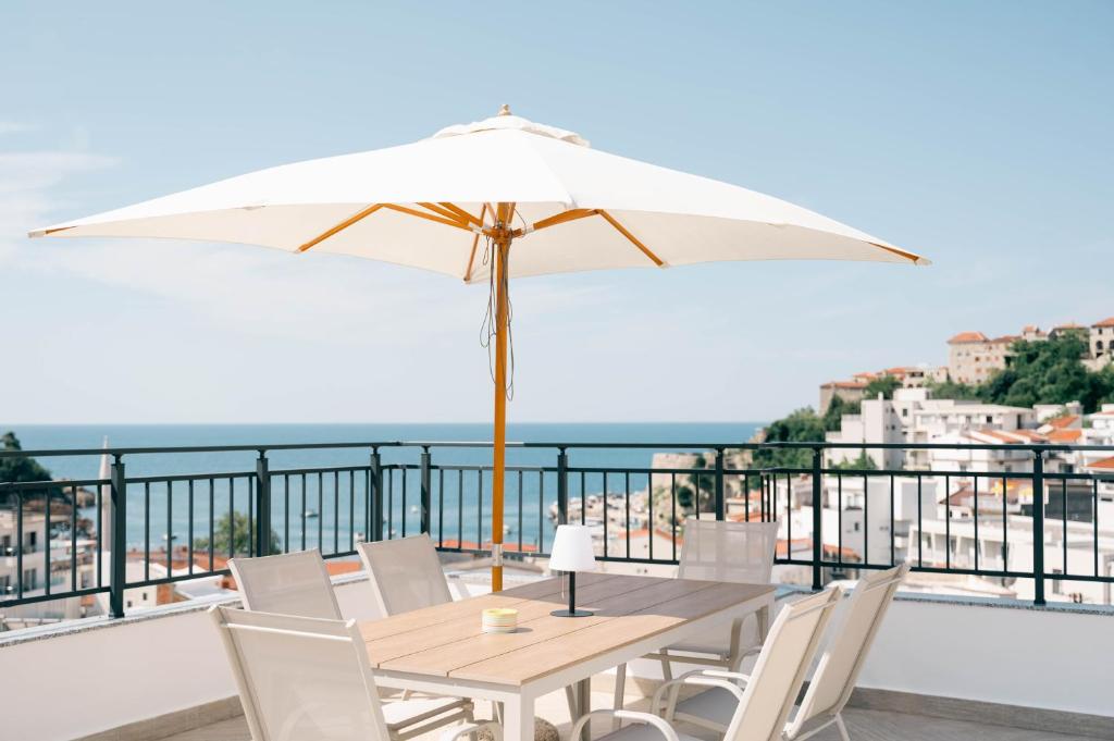 a table and chairs with an umbrella on a balcony at Laz Palace in Ulcinj