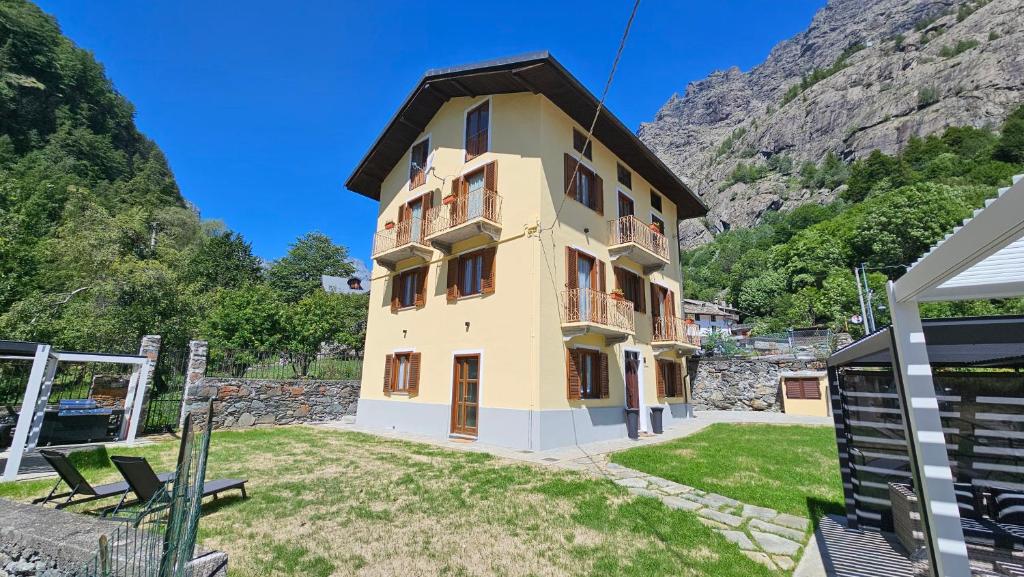 ein großes gelbes Gebäude vor einem Berg in der Unterkunft La Ràndula in Balme