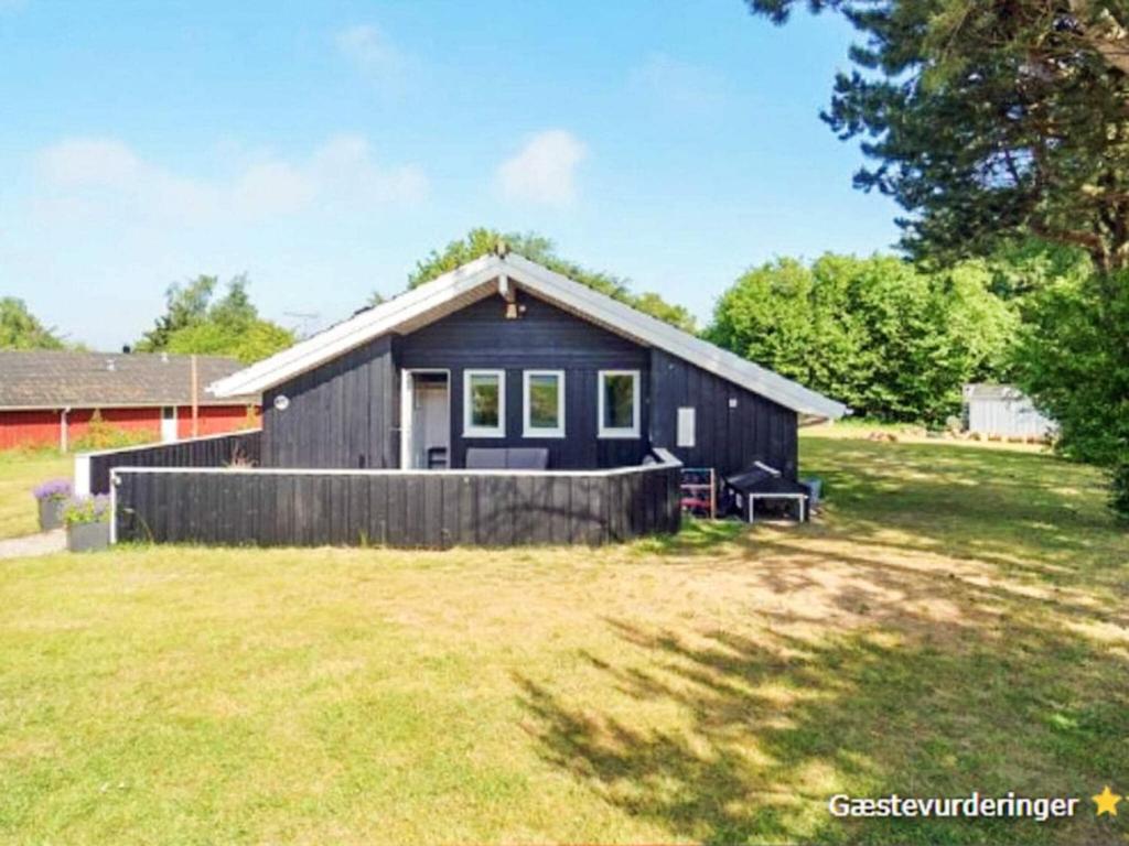 a small black house in a field with a yard at 7 person holiday home in Græsted-By Traum in Græsted