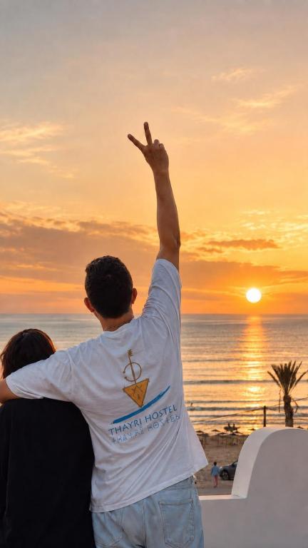 a man with his arm in the air at the beach at Thayri Hostel - Sea View in Sidi Kaouki