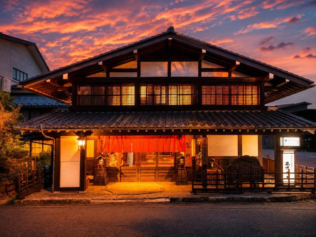 a house with a sunset in the background at Ryokan Asunaro in Takayama