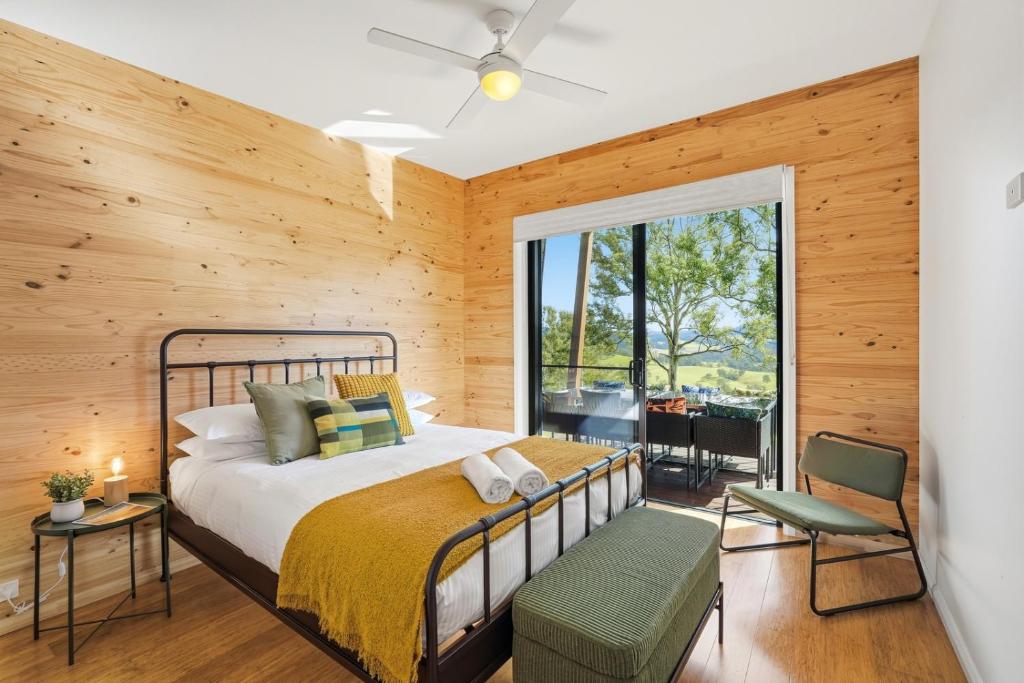 a bedroom with a bed and a large window at Hudsons Hideaway - Cosy Eco Cabin, Rainforest Walks in Dorrigo