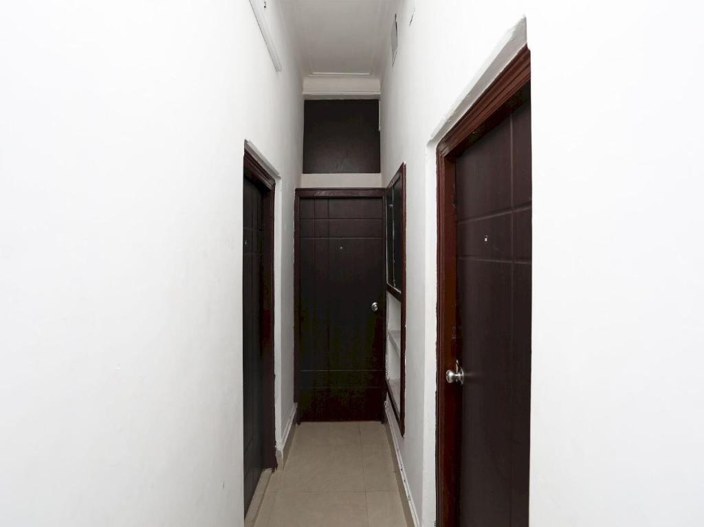 a hallway with two black doors and a bathroom at Hotel O Jalan Lake View Near Mani Square in Tangra