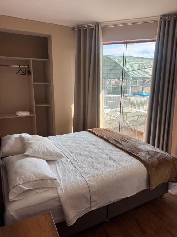 a bedroom with a bed and a large window at Hotel El Galeón in Paracas