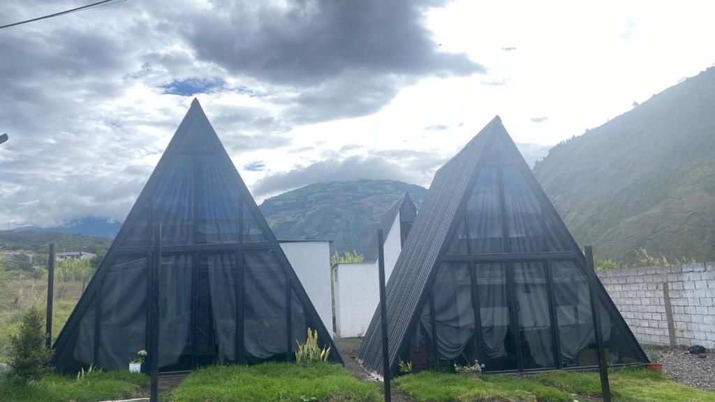 two glass structures with mountains in the background at Tungurahua Eco Lodge INN BAÑOS in Quillullaco