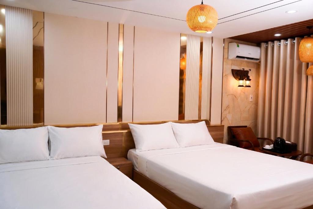 two beds in a hotel room with white sheets at Thong dong homestay&villas in Quỳnh Lưu