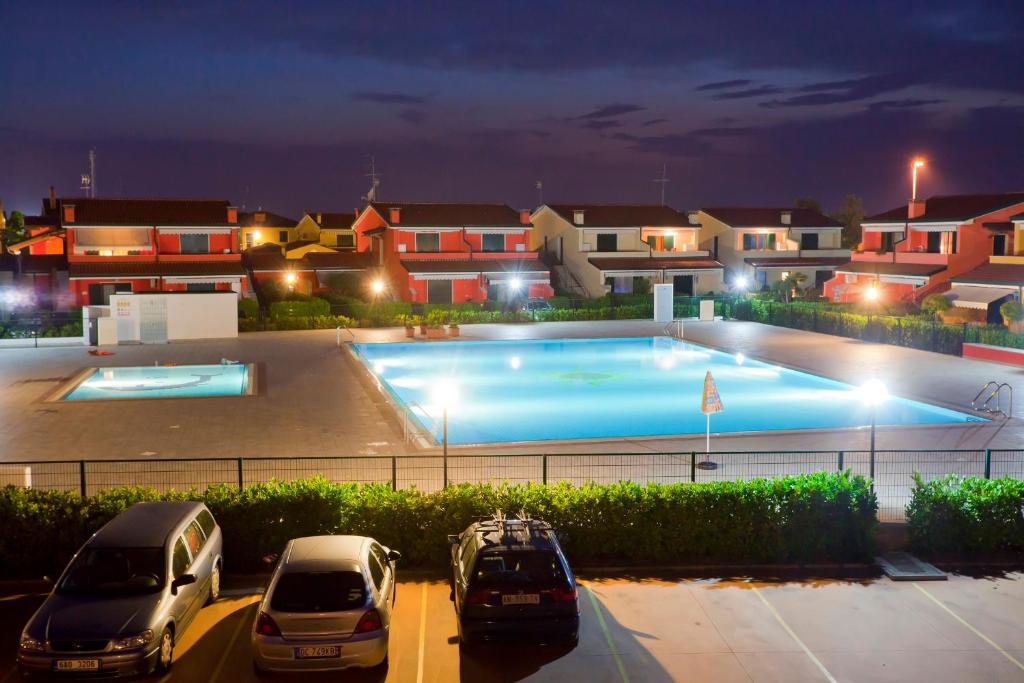 two cars parked in a parking lot next to a swimming pool at Villaggio dei Fiori Apart- Hotel 4 Stars - Family Resort-Petz Friendly-With Hypermarket-Delivery Restaurant-Pizzeria-With Breakfast Room with Supplement in Caorle