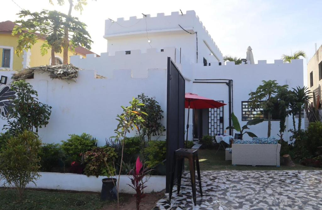 a white building with a courtyard with a red umbrella at butterfly lodge in Brufut